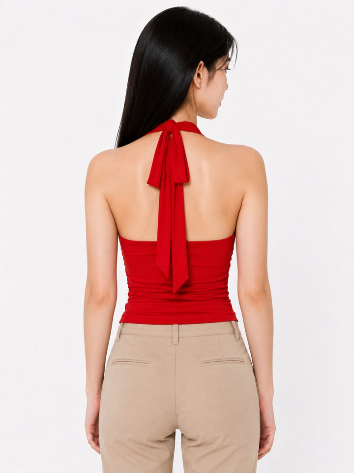 Woman wearing a red halter top with a bow detail on a white background