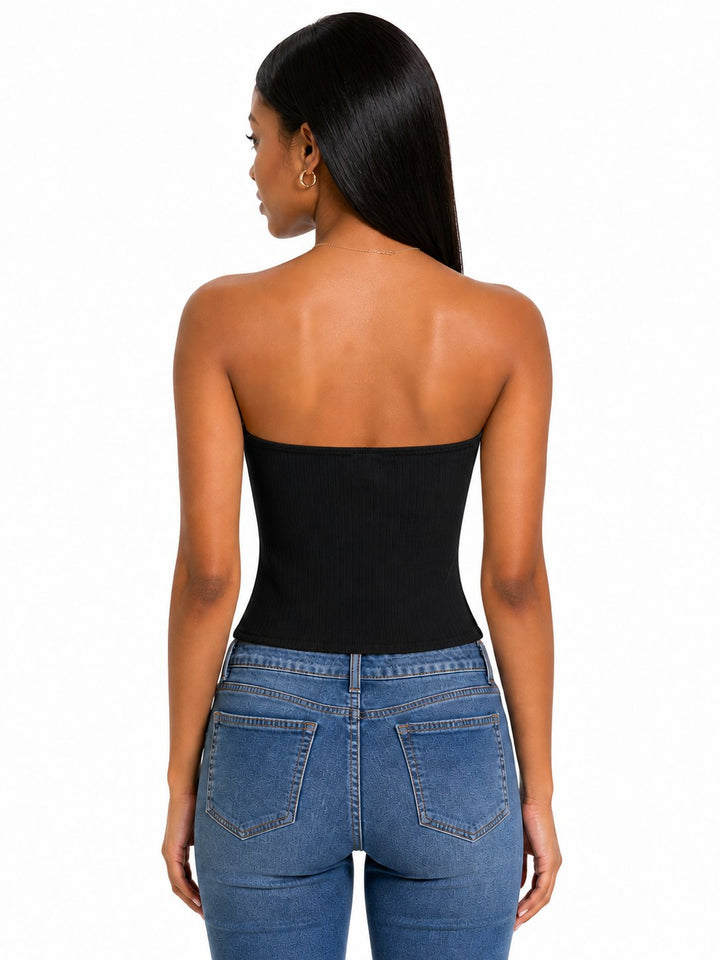 Woman wearing a black strapless top and blue jeans on a white background