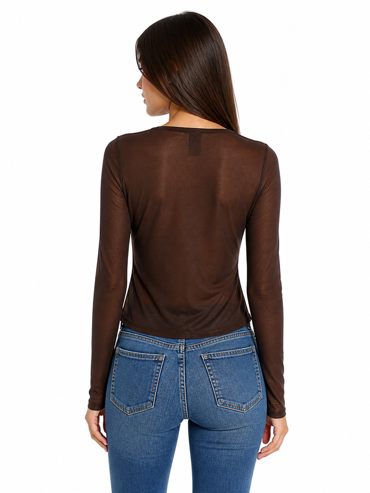 Woman wearing a brown long-sleeve sheer mesh top and blue jeans on a white background