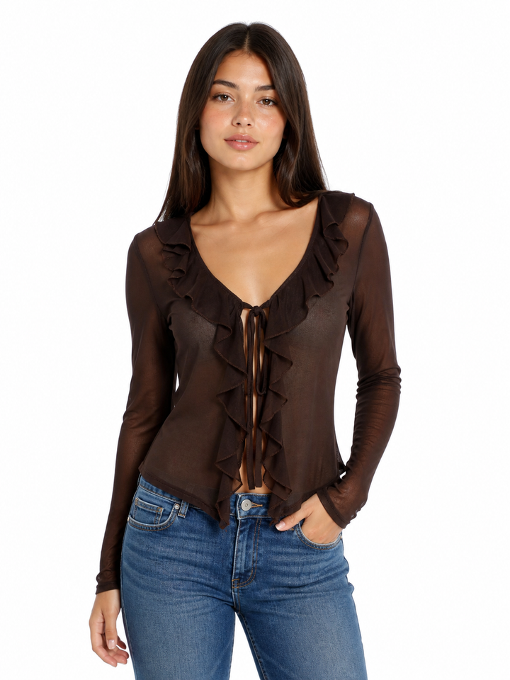 Woman wearing a brown ruffled sheer mesh blouse and blue jeans on a white background