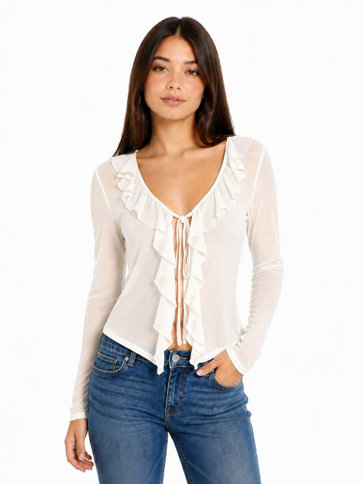 Woman wearing a white blouse with ruffles and blue jeans on a white background