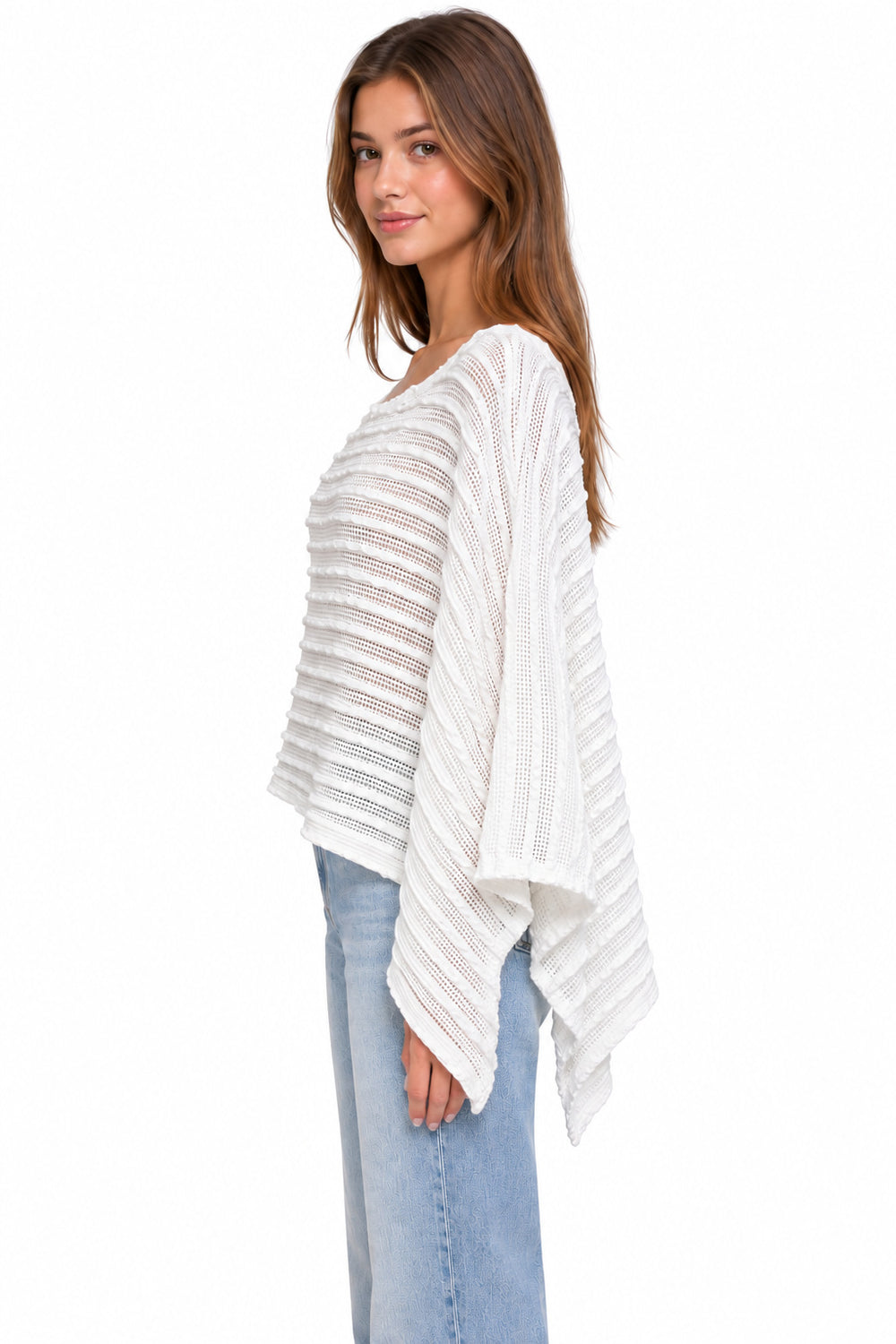 A woman wearing a white open-knit poncho-style top with wide draped sleeves and light blue jeans, shown from the side against a plain white background.