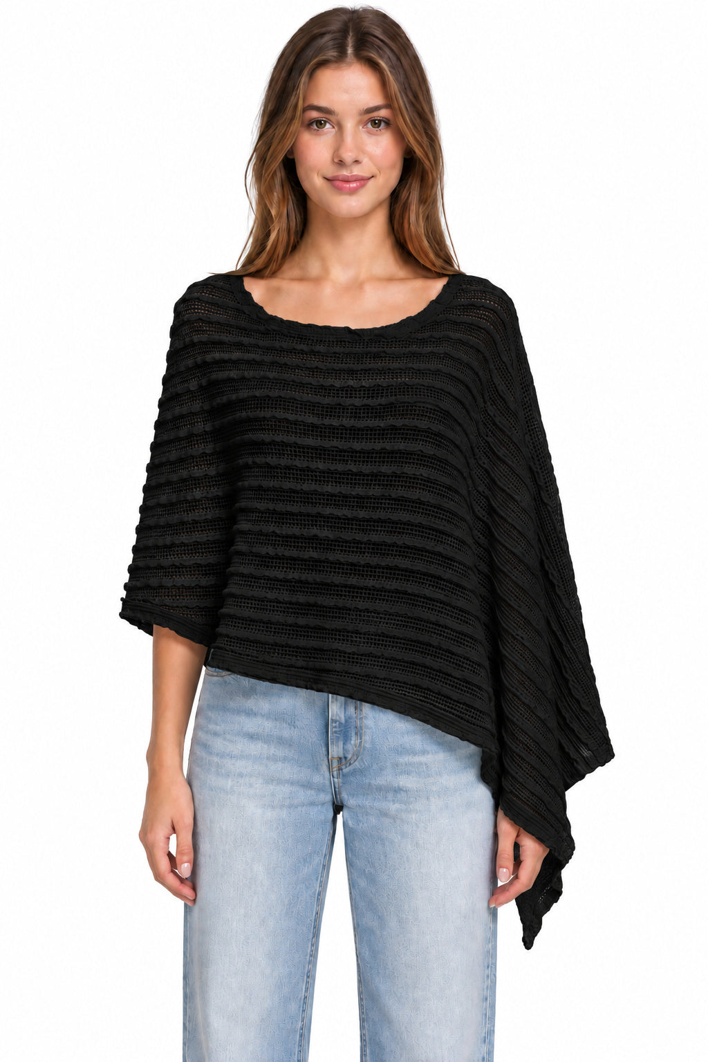 A woman modeling a black ribbed knit poncho top with a wide scoop neckline and draped sleeves, paired with light blue jeans against a plain white background.