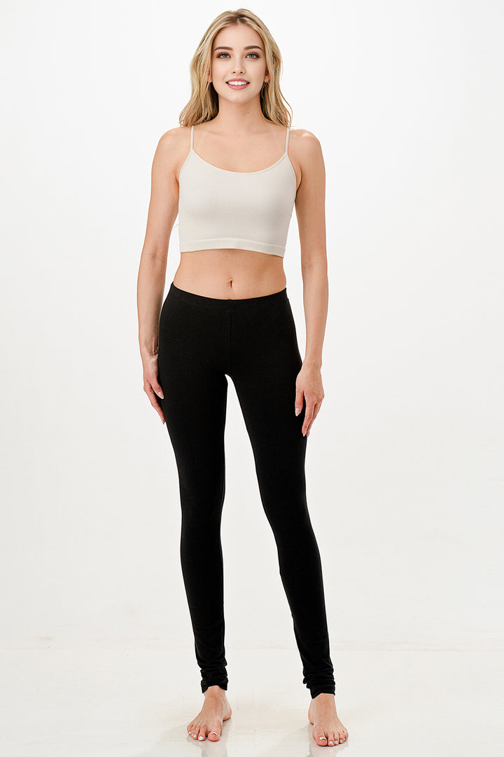 Woman wearing a white tank top and black leggings on a white background